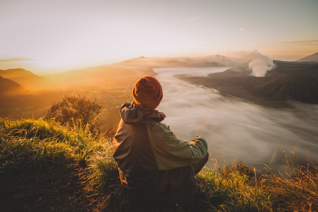 A person enjoys the sunrise view over a misty landscape in East Java, Indonesia.