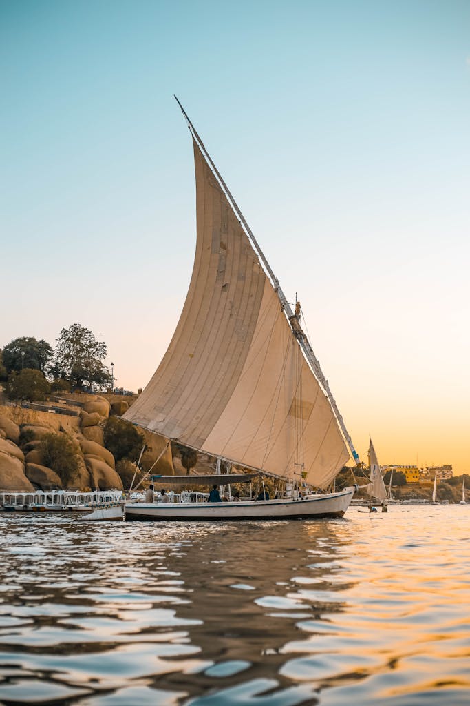 Scenic view of a traditional Egyptian felucca sailing at sunset on the Nile.